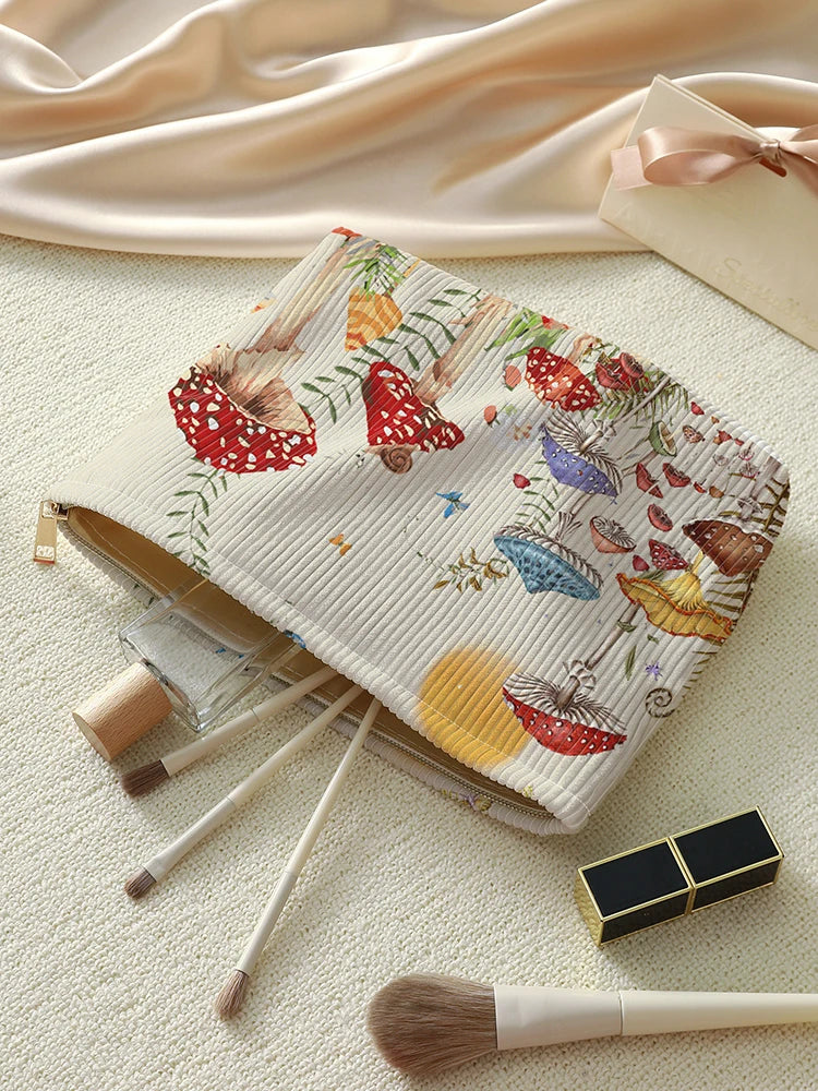 A makeup bag with a fairytale mushroom and butterfly print is shown next to makeup brushes.