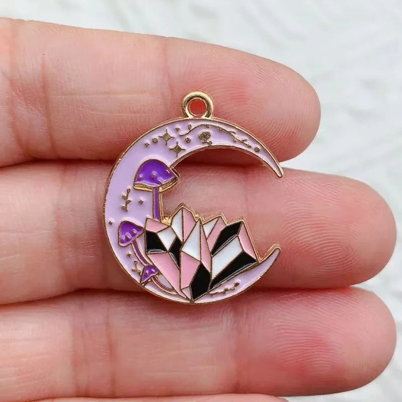 A silver-toned crescent moon charm featuring purple and pink gemstone designs for jewelry making.