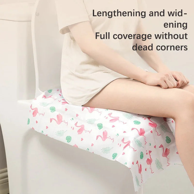 A person is using a disposable toilet seat cover with a floral pattern on a white toilet.