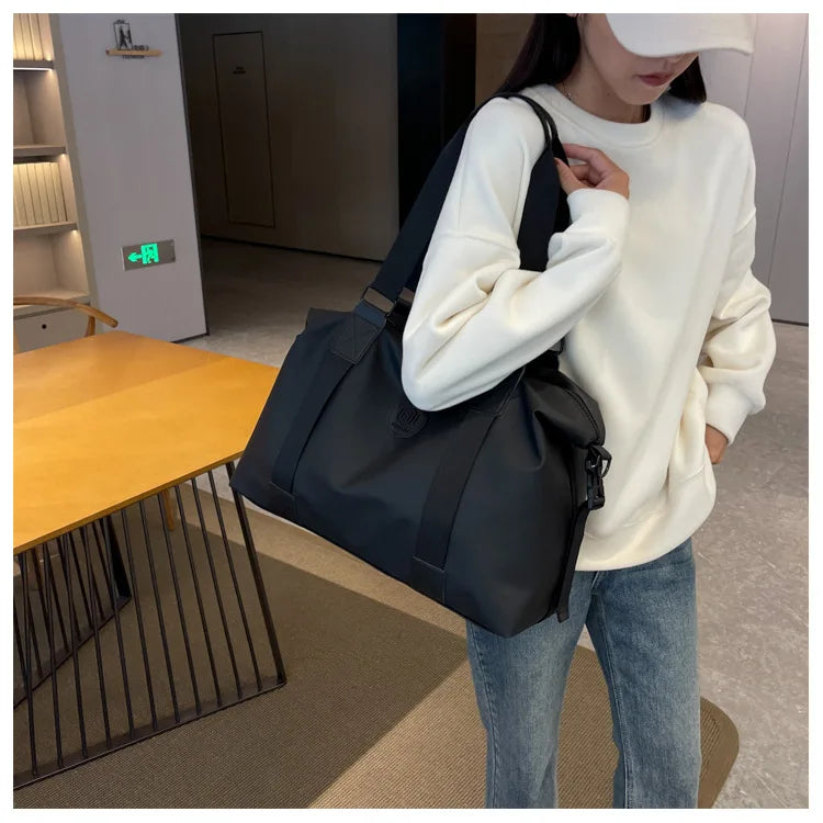 A woman holds a black Versatile Oxford Cloth Travel Tote Bag against a light background.