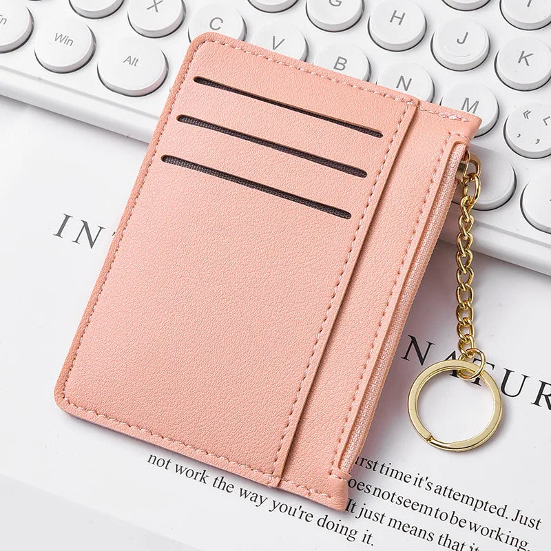 Pinkes Leder-Kartenetui mit drei horizontalen Fächern und einer goldenen Kette.