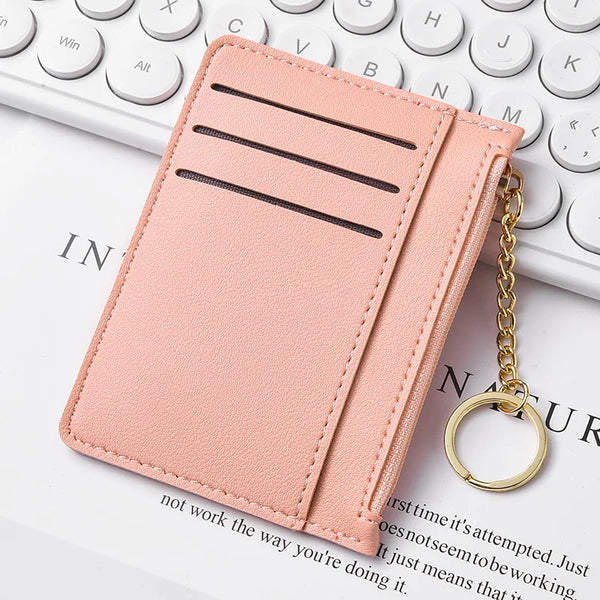 A pink leather slim card wallet with three horizontal slots and a gold chain attached.