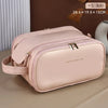 A light pink PU leather travel makeup organizer bag with double zippers resting on a beige surface.