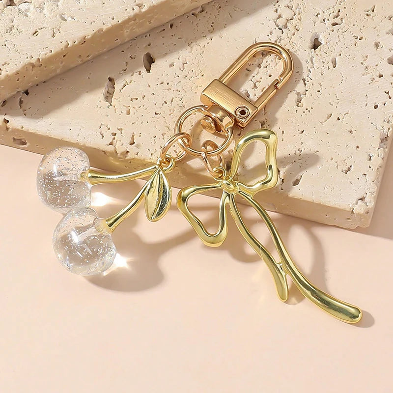 Pendentif clé en forme de cerise avec une petite perle transparente.