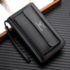 Portefeuille clutch en PU noir pour hommes avec double fermeture éclair, exposé sur une surface en bois sombre.