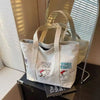 A white canvas shoulder bag featuring a Snoopy cartoon design with the text Strike Two Strike Three