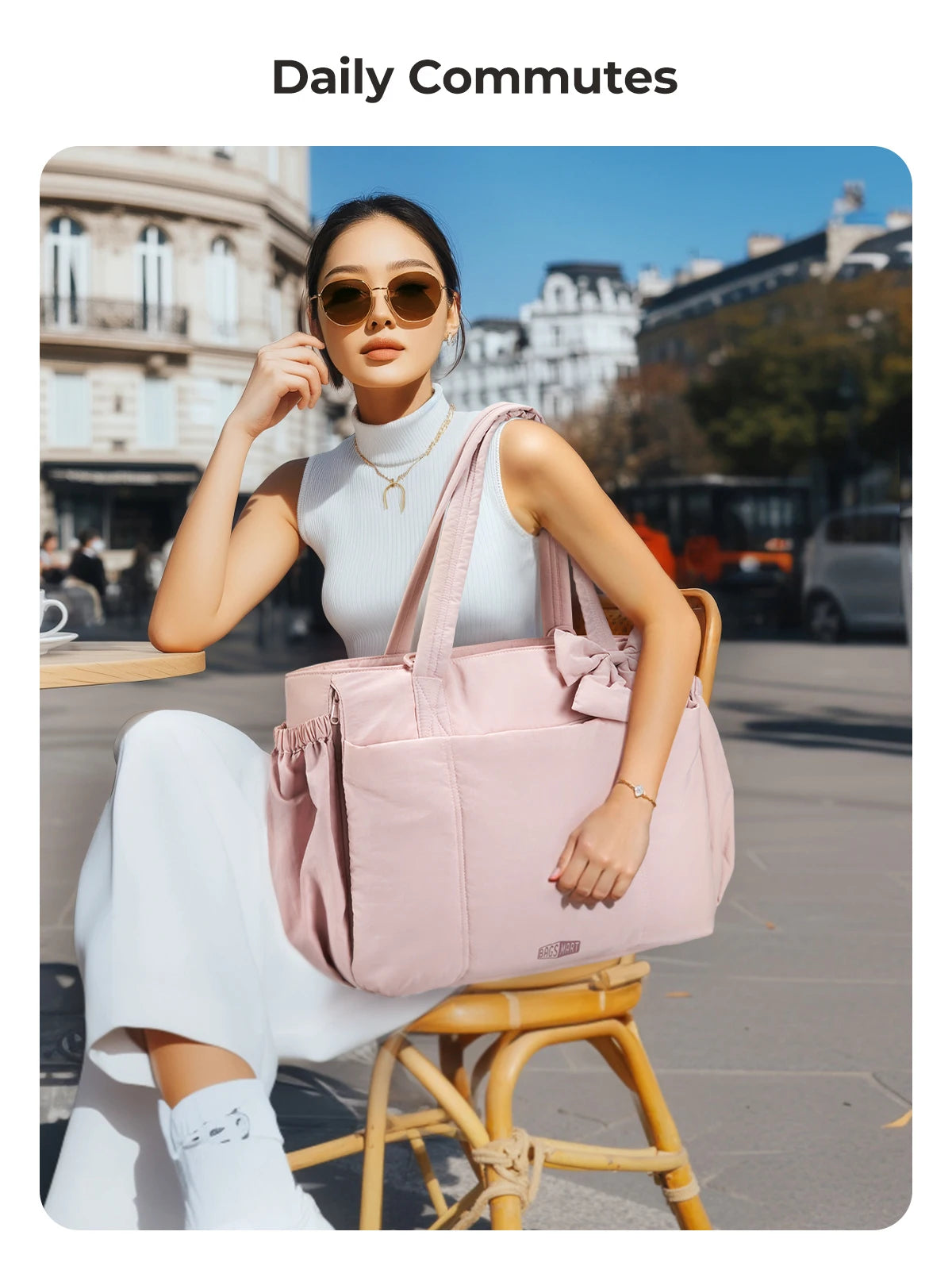A woman wearing a white top and skirt sits on a yellow chair outdoors while holding a pink large capacity tote bag.