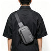 A person wearing a black shirt is shown from the back, carrying a gray chest bag across their back.