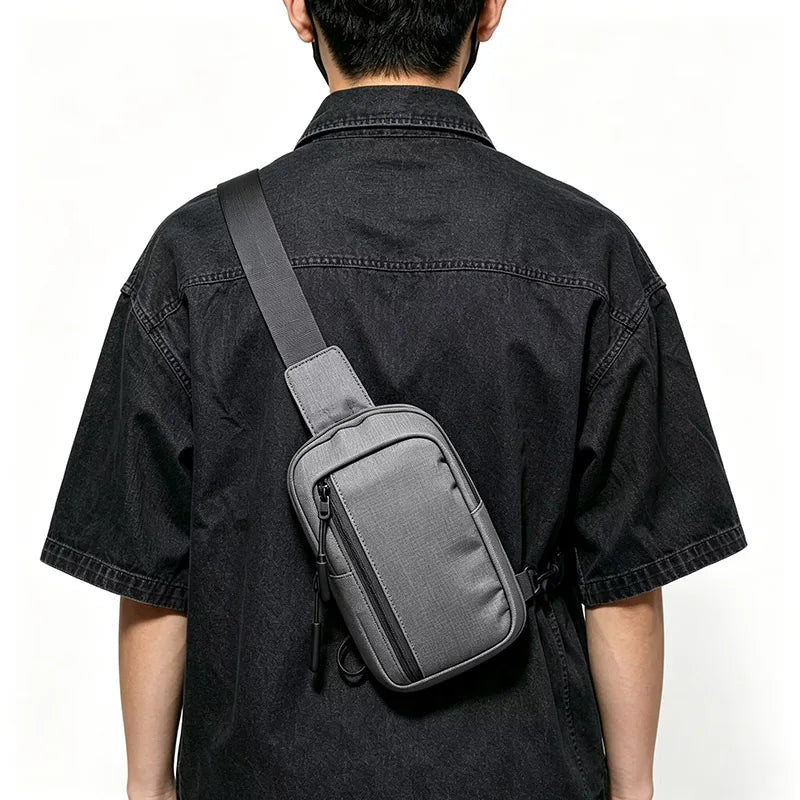 A person wearing a black shirt is shown from the back, carrying a gray chest bag across their back.