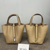 A beige genuine leather bucket bag with a drawstring closure and gold hardware displayed on a gray surface.