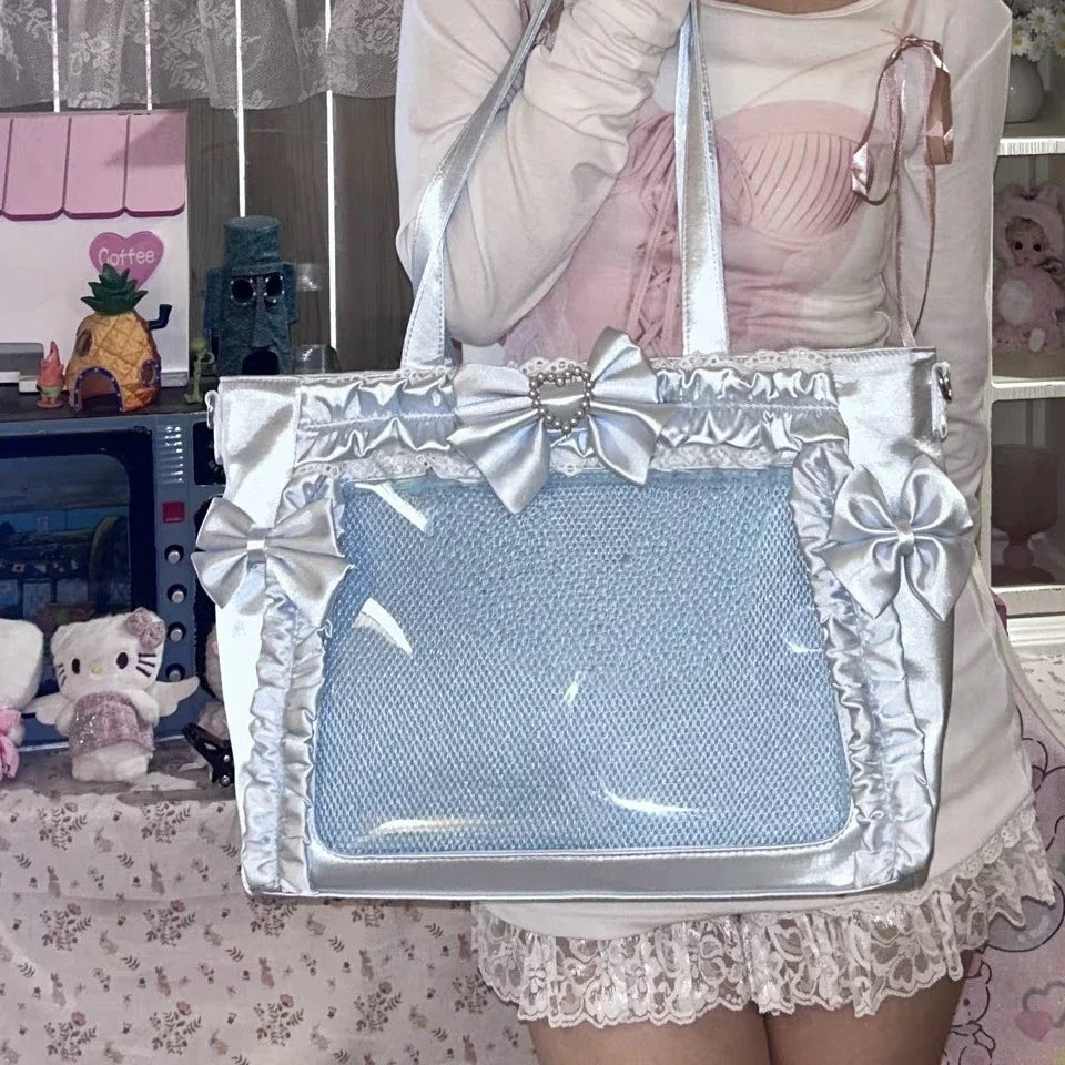 A light blue transparent shoulder tote bag with silver trim and a large bow, held by a person.