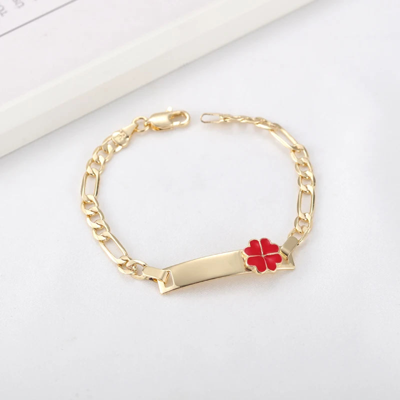 A gold chain bracelet with a red heart charm on a white background.