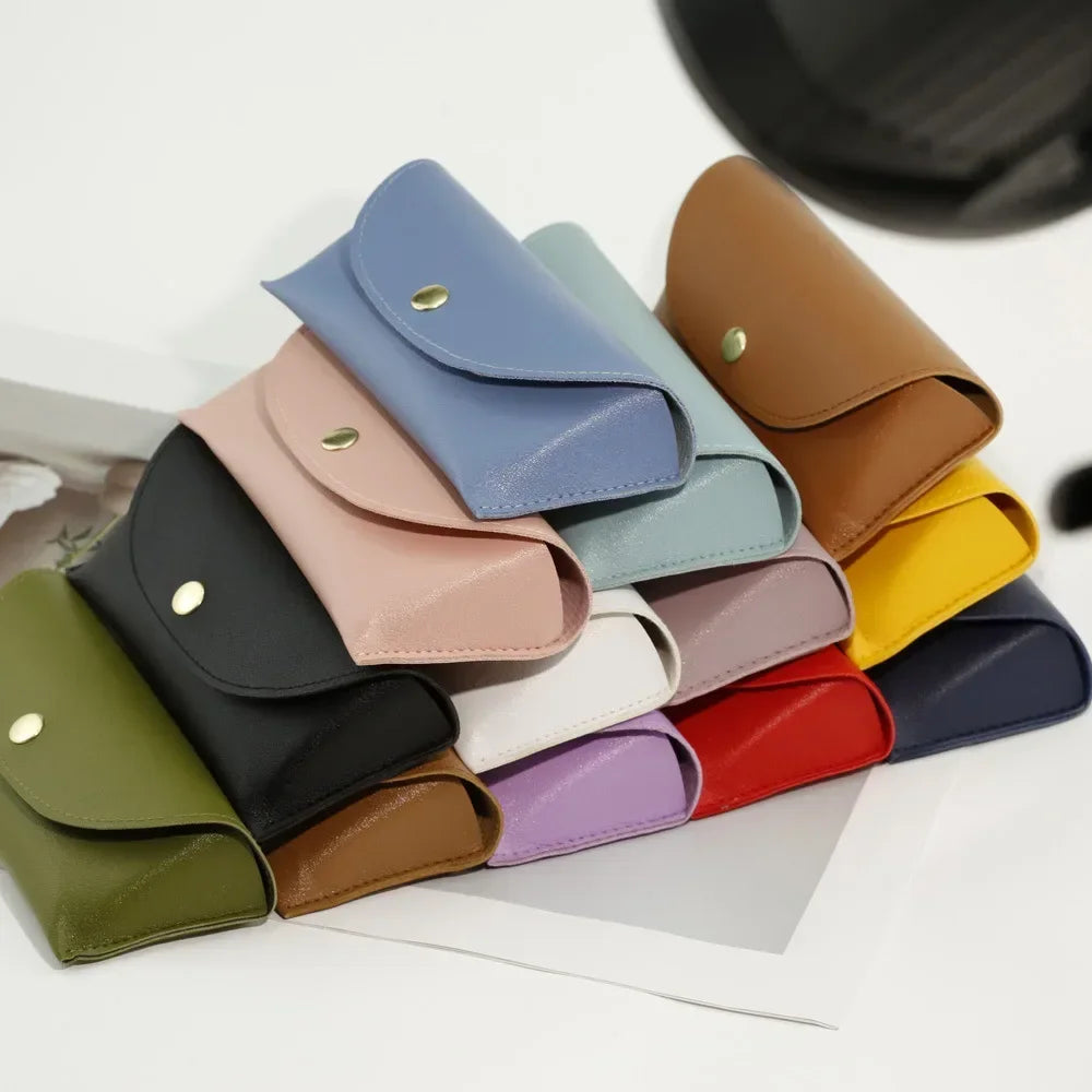 A collection of PU leather hard shell sunglasses cases in various muted colors laid out on a white surface.
