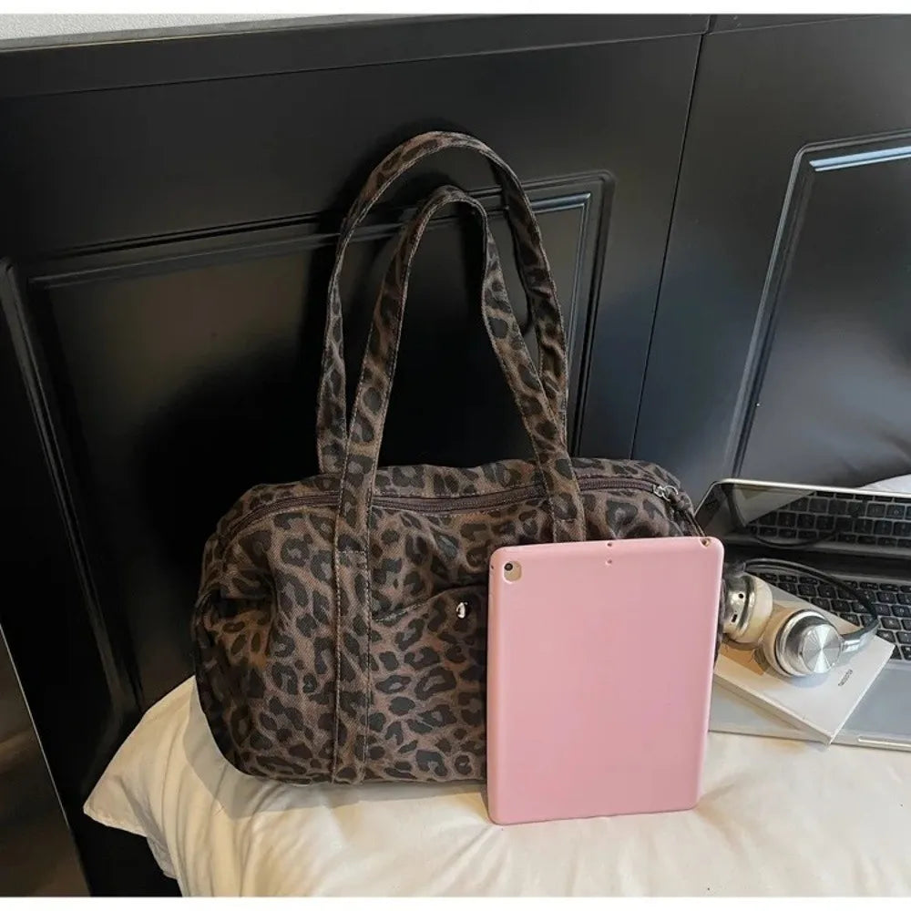 A pink tablet is placed in front of a brown leopard print canvas tote bag on a white surface.