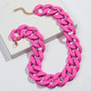 A pink matte acrylic chain necklace with a gold-colored clasp is displayed on a white box.