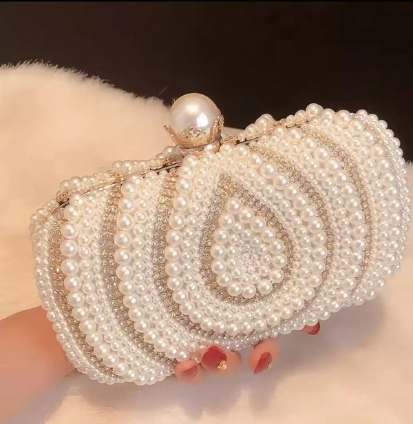 A round, pearl-embellished shoulder clutch bag with a gold chain and a pearl drop detail.