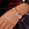 A gold charm bracelet featuring Halloween pumpkin and ghost motifs on a wrist.