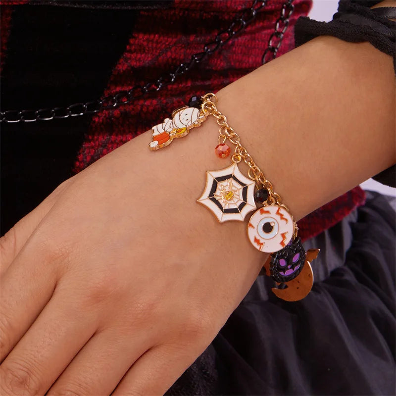 A gold charm bracelet featuring Halloween pumpkin and ghost motifs on a wrist.