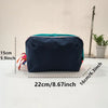 Navy blue lightweight travel makeup bag with teal trim shown on a white surface.