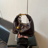 A dark brown retro PU leather shoulder bag with gold hardware is held by a hand against a gray background.