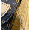 Primer plano de un bolso cruz de textura floral azul oscuro con correa de cadena dorada y acento de cuero beige claro.