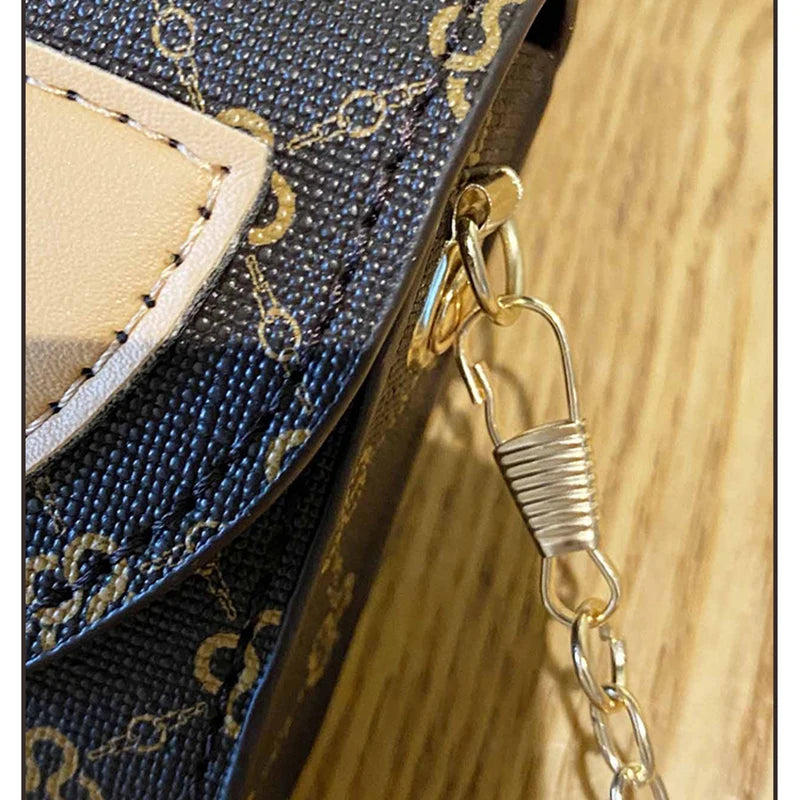 Primer plano de un bolso cruz de textura floral azul oscuro con correa de cadena dorada y acento de cuero beige claro.