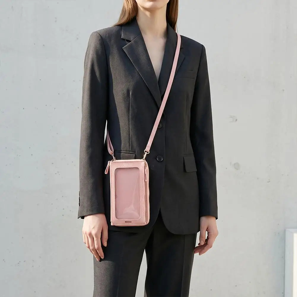 Eine Frau in einem dunkelgrauen Blazer und Hosen, die eine pinke Touchscreen-Crossbody-Handytasche trägt.