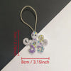 Hand sewn rhinestone beaded bag charm shaped like a small, purple and white creature.
