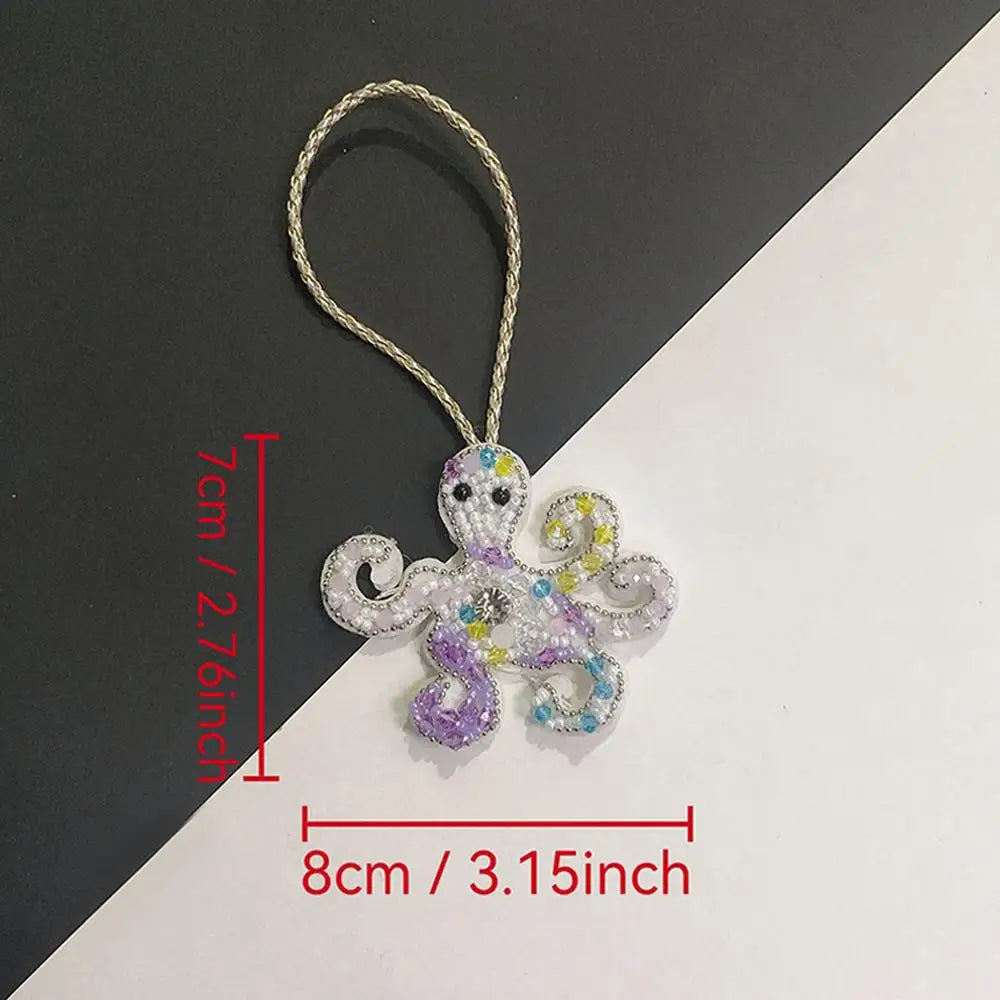 Hand sewn rhinestone beaded bag charm shaped like a small, purple and white creature.