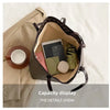 A faux leather letter-print tote bag is shown open, displaying various small items like a smartphone and notebook.