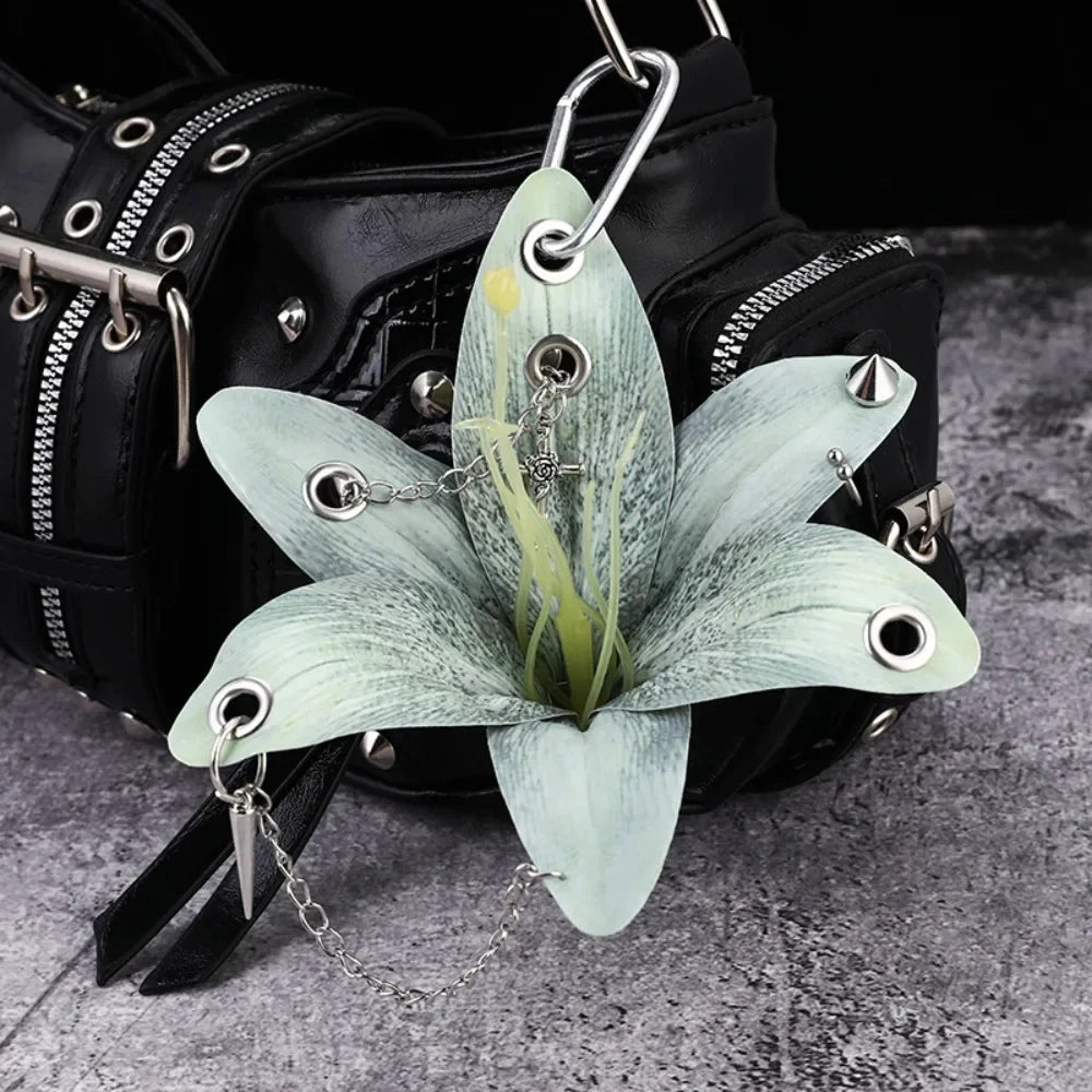 A realistic pale green phalaenopsis orchid flower keychain attached to a black leather backpack.