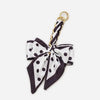 A black and white polka dot fabric bow strap with a gold-toned metal clasp.