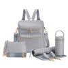 A light gray large capacity diaper bag backpack with straps and storage compartments is shown next to rolled-up fabric.
