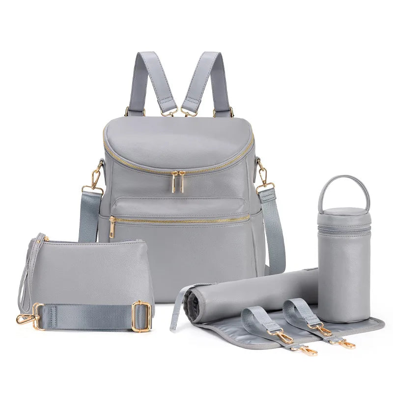 A light gray large capacity diaper bag backpack with straps and storage compartments is shown next to rolled-up fabric.
