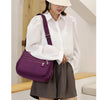 A woman wearing a white shirt and skirt holds a purple waterproof nylon crossbody shoulder bag.