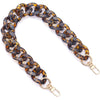 A close-up of a gold-toned acrylic chain strap with a dark leopard print pattern.