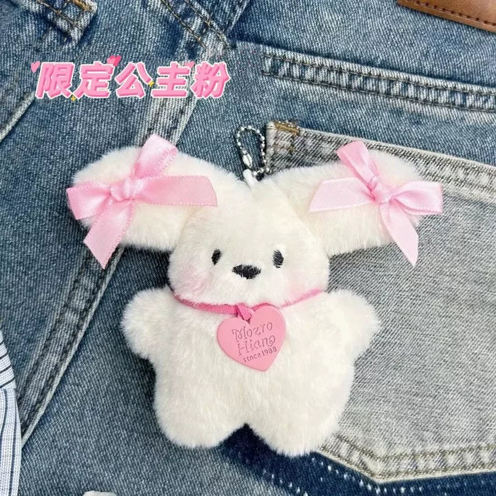 A white rabbit charm with pink bows is attached to a denim jacket.