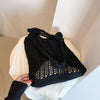 A black bohemian knit shoulder bag is displayed on a white surface.
