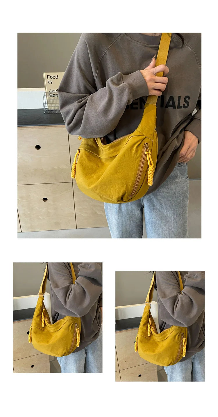 Eine Frau hält eine senffarbene Nylon-Crossbody-Handtasche mit goldenen Schnüren vor ihren Körper.