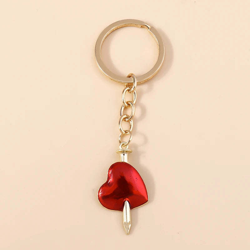 Gold chain keychain featuring a red heart pendant with a silver sun eye charm.