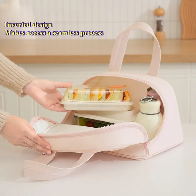 A hand is opening a pink insulated lunch tote with an inverted design to access contents easily.