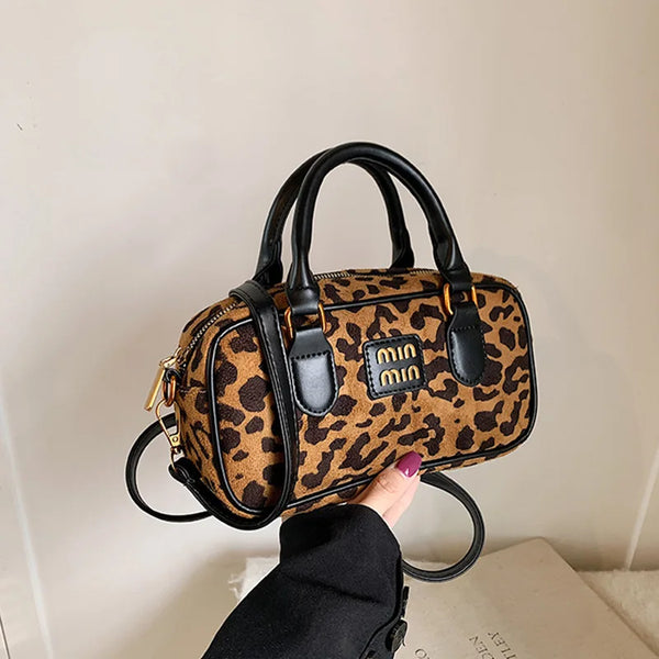 A brown and black leopard print designer hobo bag being held by a person.