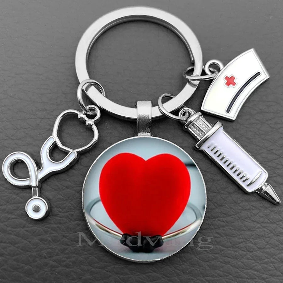 Silver keychain featuring a heart and a medical symbol, including a stethoscope and a syringe charm.