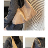 A beige suede shoulder tote bag carried by a person wearing a gray sweater.
