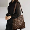 A woman wearing a black sheer top and long black skirt carries a brown leather backpack.