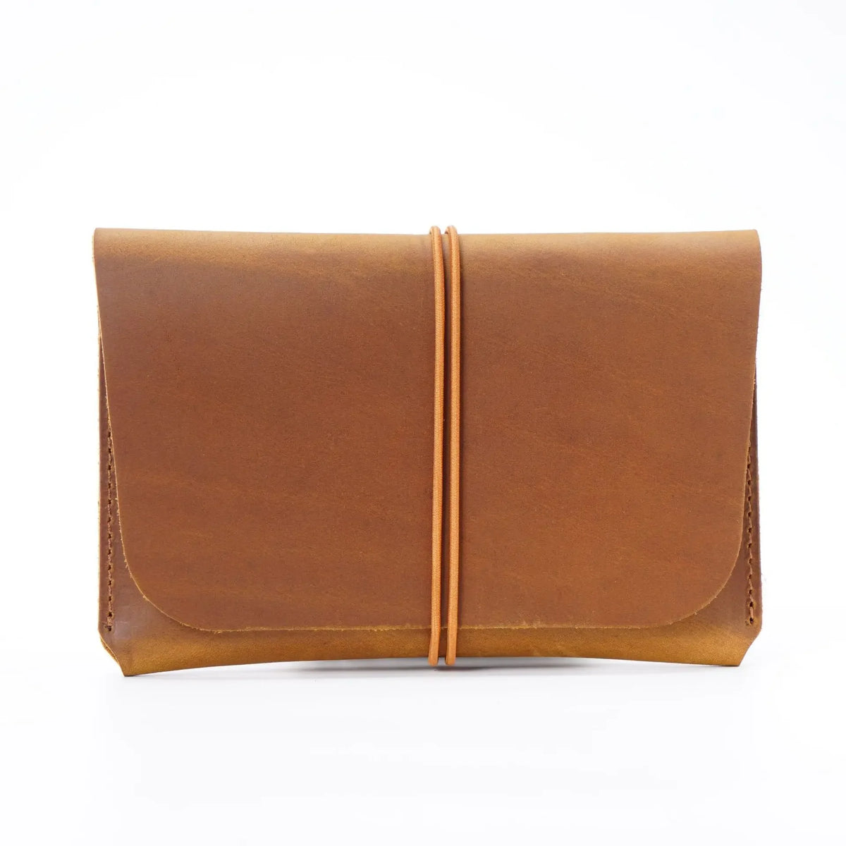 A minimalist full-grain leather passport holder and card wallet in a warm tan brown color.