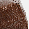 Close-up of a brown crocodile print leather tote bag detail.