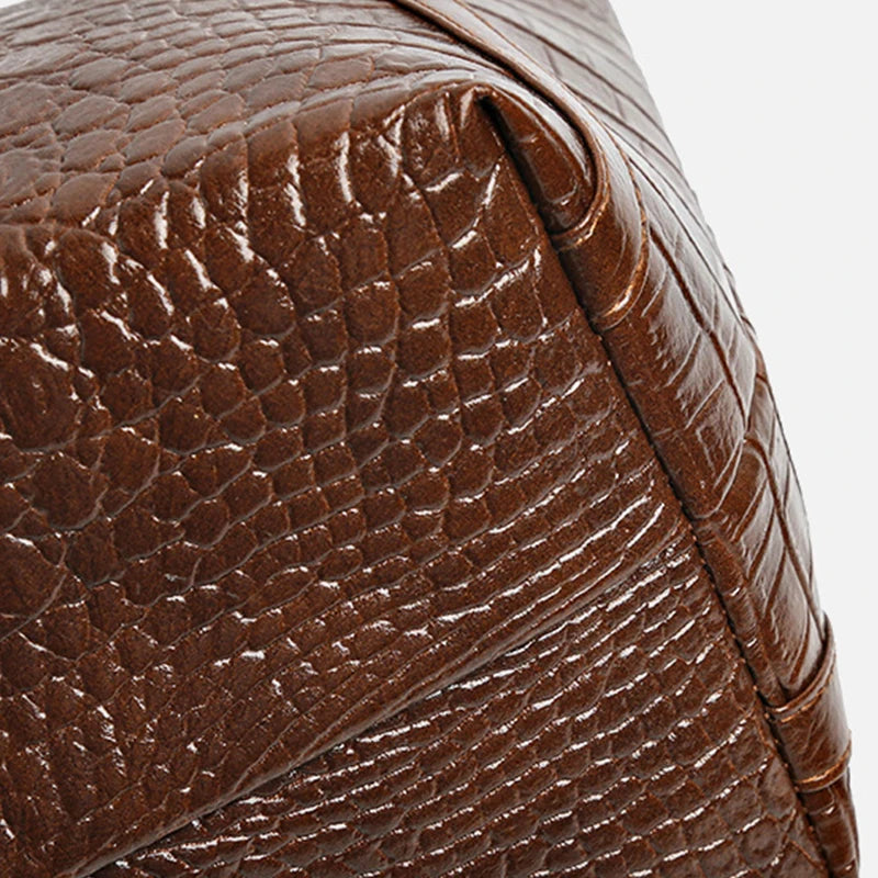 Close-up of a brown crocodile print leather tote bag detail.