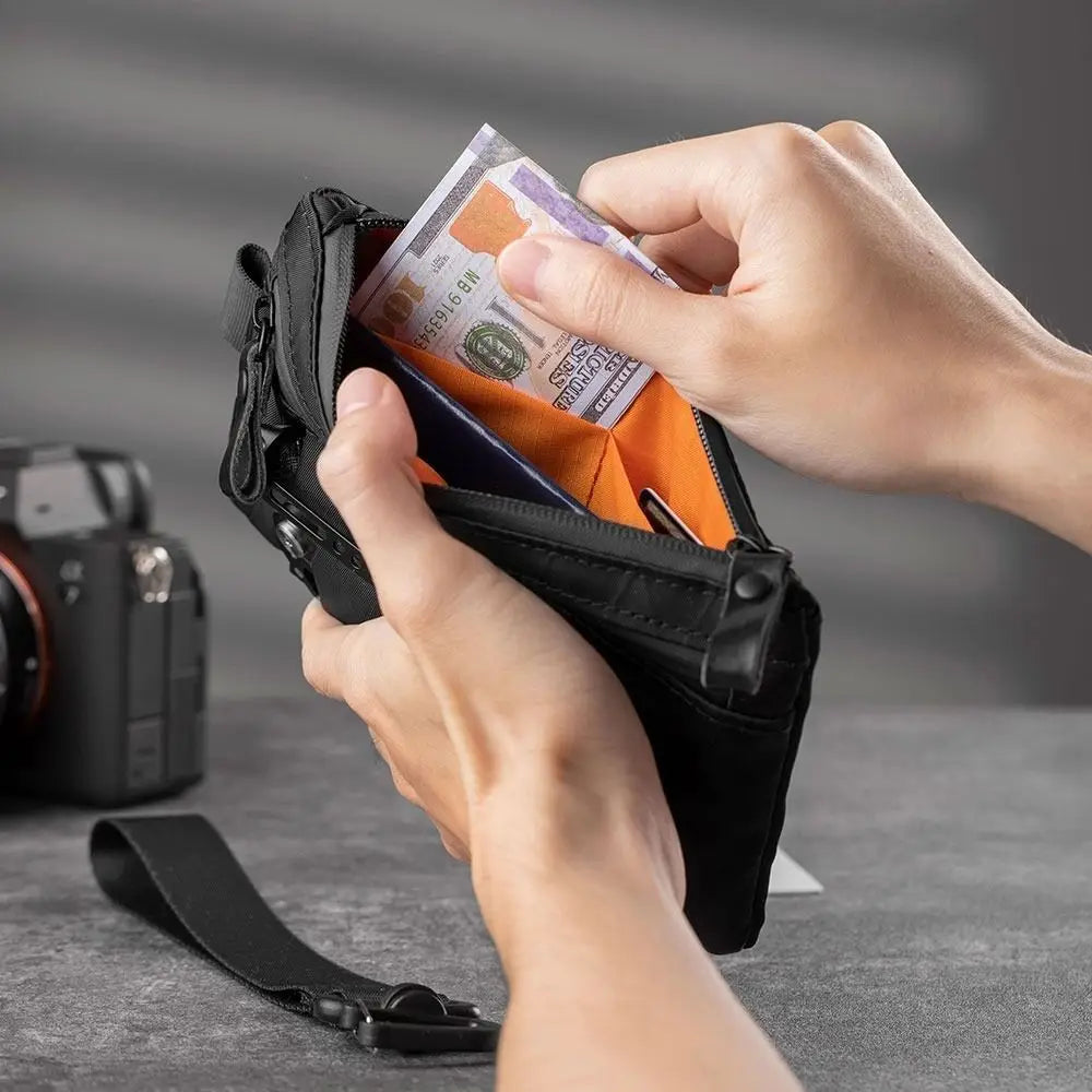 Eine Hand steckt Bargeld in eine schwarze RFID-blockierende Herren-Reisewallet und Kartenhalter.