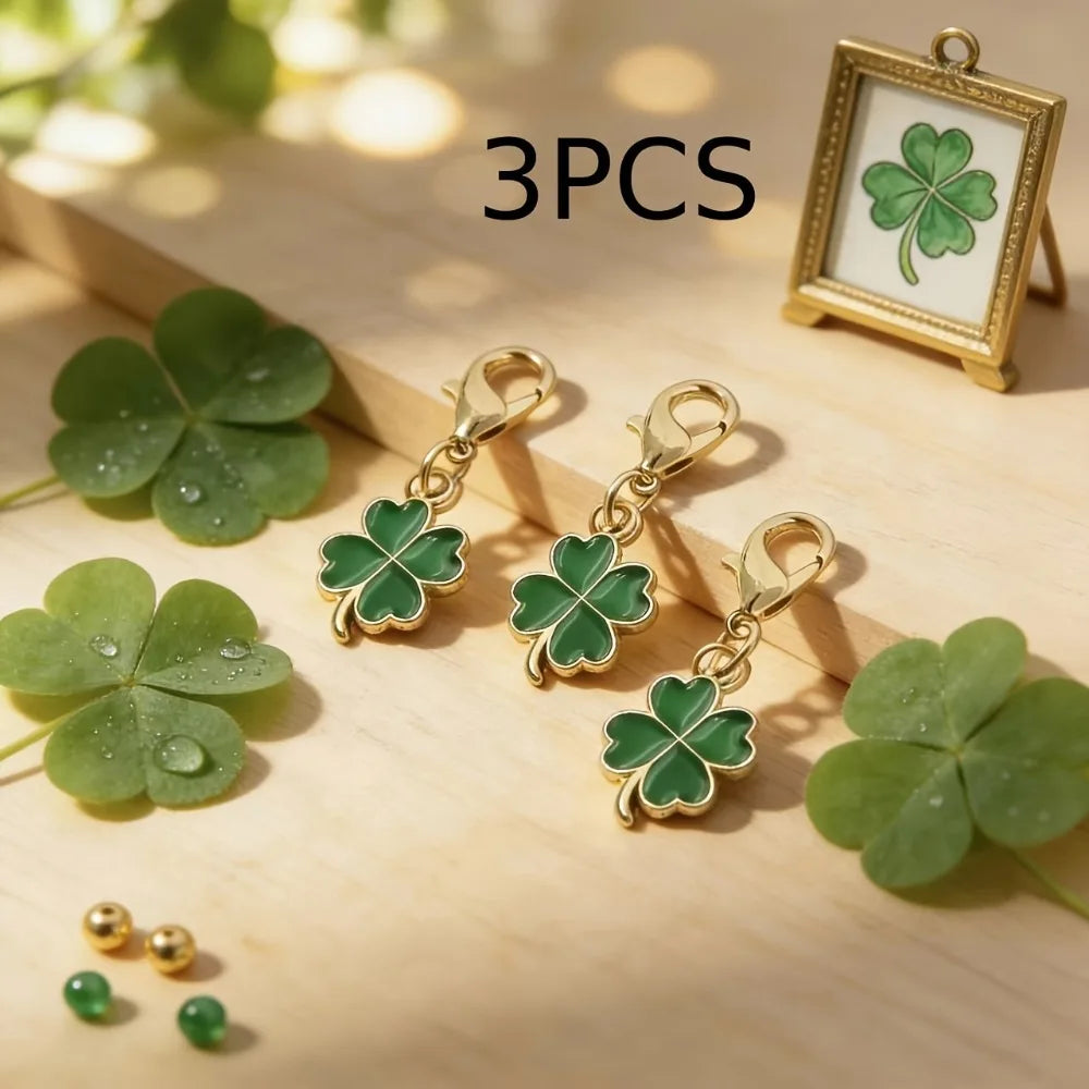 Three gold-toned four leaf clover keychains displayed on a wooden surface with a framed clover.